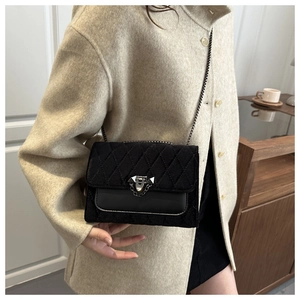 Detail of black quilted velvet crossbody bag with silver lock and chain strap