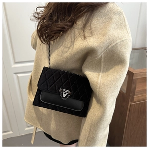 Detail of black quilted chain bag featuring silver clasp and velvet texture on model