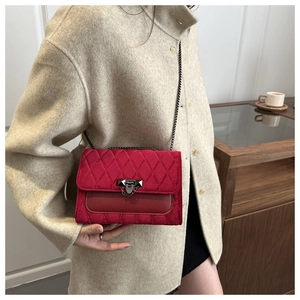 Detail of red quilted chain bag showing the turn-lock clasp and matte texture on model