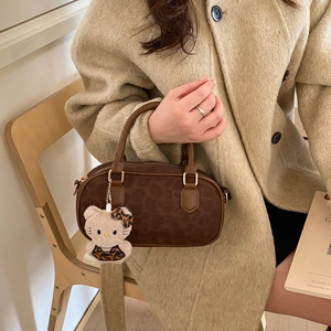 Borsa a bauletto marrone con stampa a pois e ciondolo in peluche tenuta da una donna