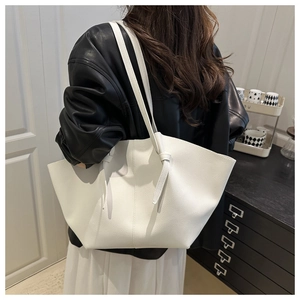 Détail d'un grand cabas blanc avec texture litchi et bandoulière nouée sur modèle