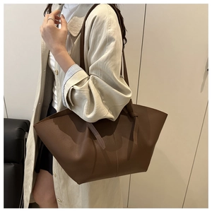 Sac fourre-tout marron foncé avec texture cuir grainé et détail de nœud sur la sangle