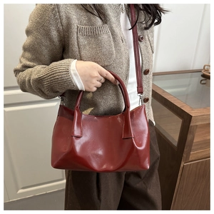Detail of wine red glossy leather tote bag with metallic buckles and slim shoulder strap