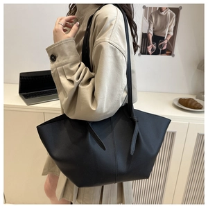Détail du sac cabas en cuir grainé noir avec nœud décoratif sur la bandoulière réglable
