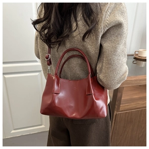 Deep red bucket bag styled on a shoulder with minimalist dark brown winter sweater