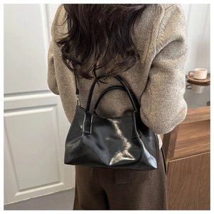 Rear view of a model carrying a black pleated bucket bag with adjustable shoulder strap