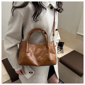 Close-up of caramel brown bucket bag with smooth faux leather texture and round handles