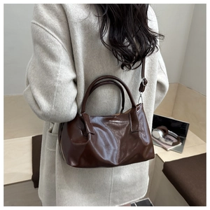 Detail of coffee glossy PU leather tote bag with adjustable strap on a wool coat