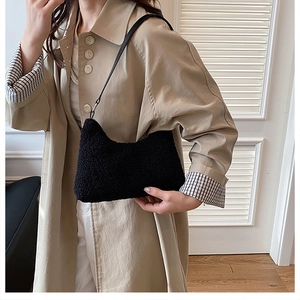 Detail of a black faux shearling hobo bag with leather strap worn with a trench coat
