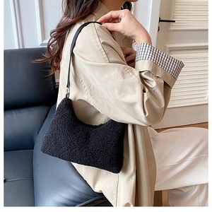 Detail of black faux shearling shoulder bag with leather strap on a beige trench coat