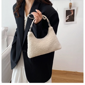 Minimalist white faux fur hobo bag shown being carried by a model in a black blazer