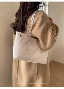White minimalist tote bag with silver metal eyelets and adjustable strap on a model