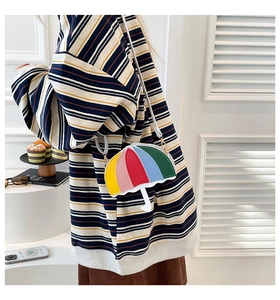Detail of umbrella-shaped crossbody bag with vibrant colorful stitching and white strap