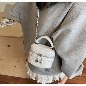 Detailed shot of white quilted mini chain bag with silver heart pendant zipper on a model