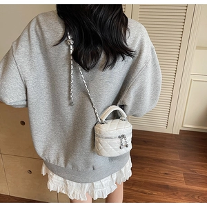 Detailed back view of a white quilted mini bucket bag with heart-shaped zipper puller