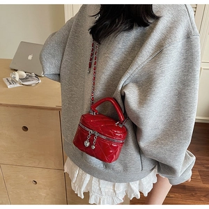 Close-up of red quilted leather mini box bag featuring heart charms and silver chain