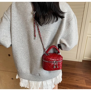 Close-up of red patent leather mini box bag with heart charm and quilted chain strap