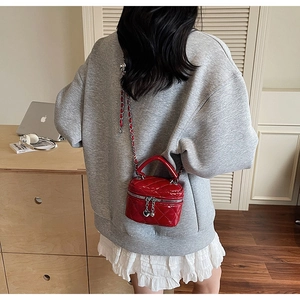 Detailed view of red quilted chain box bag with heart charm and silver metal strap