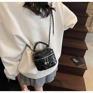 Close-up of mini black quilted bucket bag with silver chain and heart-shaped zipper pull