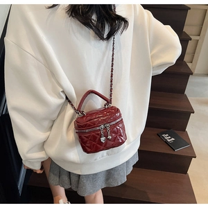 Detail of dark red quilted mini box bag with heart zippers and chain strap