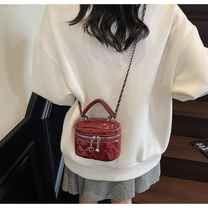 Detail of burgundy quilted box bag with chain strap and glossy patent finish