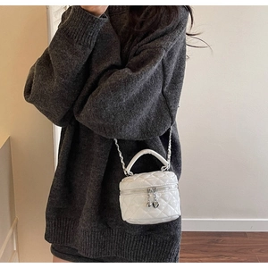 Close-up of white quilted mini box bag featuring double heart pendants and chain strap