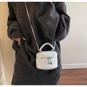 Close-up of white quilted leather round mini bag with heart zipper pull and chain strap