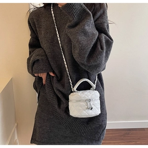 Close-up of a white quilted leather mini crossbody vanity bag with silver chain straps