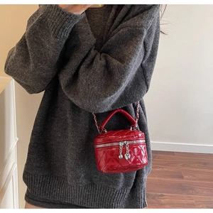 Detail of red quilted mini box bag with heart zipper pull and leather chain strap