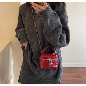 Detail of red quilted mini box bag with heart zipper and chain strap on grey knit dress
