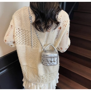 Silver quilted mini vanity case bag with chain strap and heart charm on stairs