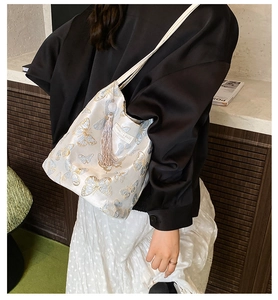 Détail de la broderie papillon sur sac cabas en soie avec pompon rose et étiquette cuir
