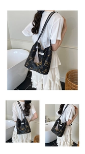 Detail of black tote bag with gold butterfly prints and a silver tassel charm