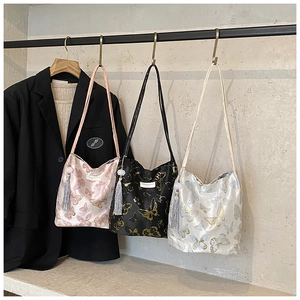Detailed view of silk shoulder bags with golden butterfly embroidery and tassel charms