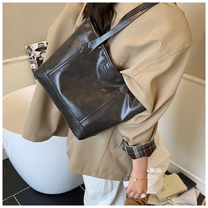 Detail of dark brown vintage tote bag with FASHION embossed logo and smooth PU leather