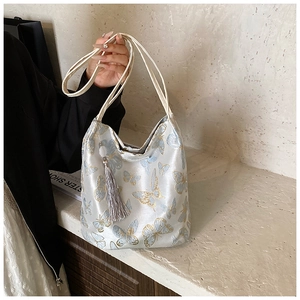Detail of silk bucket bag with delicate butterfly embroidery and long grey tassel charm