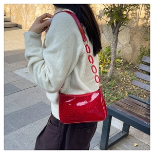 Détail du sac baguette rouge effet serpent avec sa bandoulière à maillons assortis