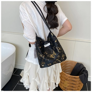 Détail du sac cabas noir avec broderie papillon dorée et pendentif à pampille élégant