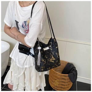 Detail of black embroidered tote bag with golden butterfly print and tassel charm