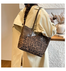 Détail du sac cabas léopard avec bordure en cuir marron porté à l'épaule du mannequin
