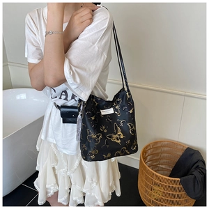 Détail du sac cabas en toile noir avec motifs de papillons dorés et pompon argent