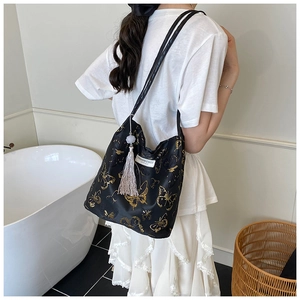 Detail of black tote bag with gold butterfly patterns and stylish tassel accessory