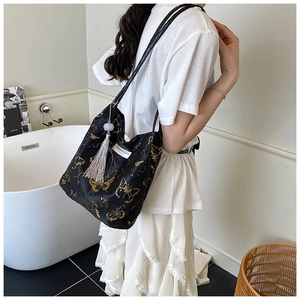 Détail d'un sac cabas noir avec broderie papillon dorée et pampilles à franges