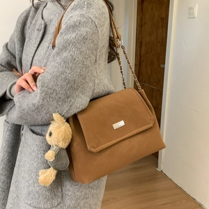 Borsa sottobraccio in pelle marrone con catena argento e ciondolo coniglio su cappotto