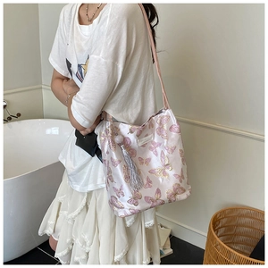 Detailed close-up of light pink satin tote bag with exquisite butterfly embroidery and fringe