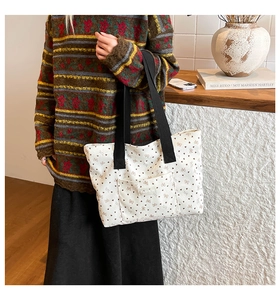 Close-up of cream canvas tote bag with heart and bow patterns on a wooden counter
