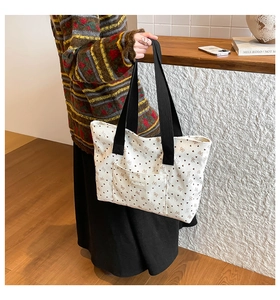 Detail of corduroy tote bag featuring brown bow prints and a fashion label on the front pocket