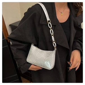 Detail view of white snakeskin texture handbag with gold and silver chain strap for women