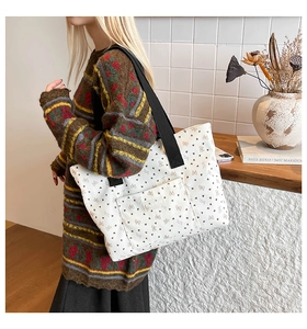 Close-up of white canvas tote bag with brown heart patterns and FASHION label detail