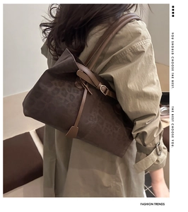 Detail of dark brown leopard print tote bag with leather strap and metal buckle